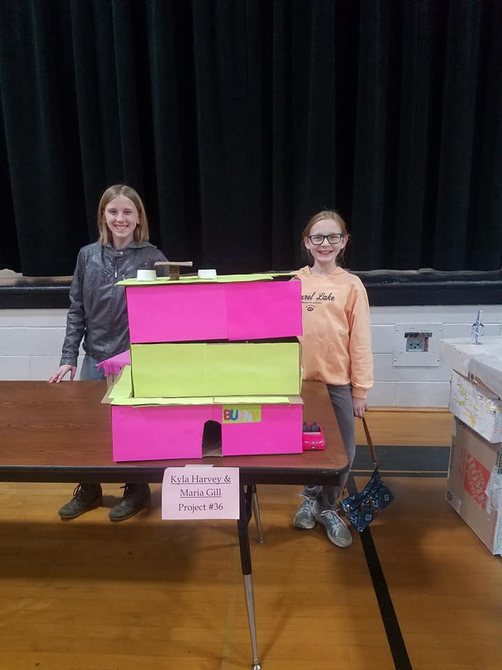 two girls behind a cardboard project